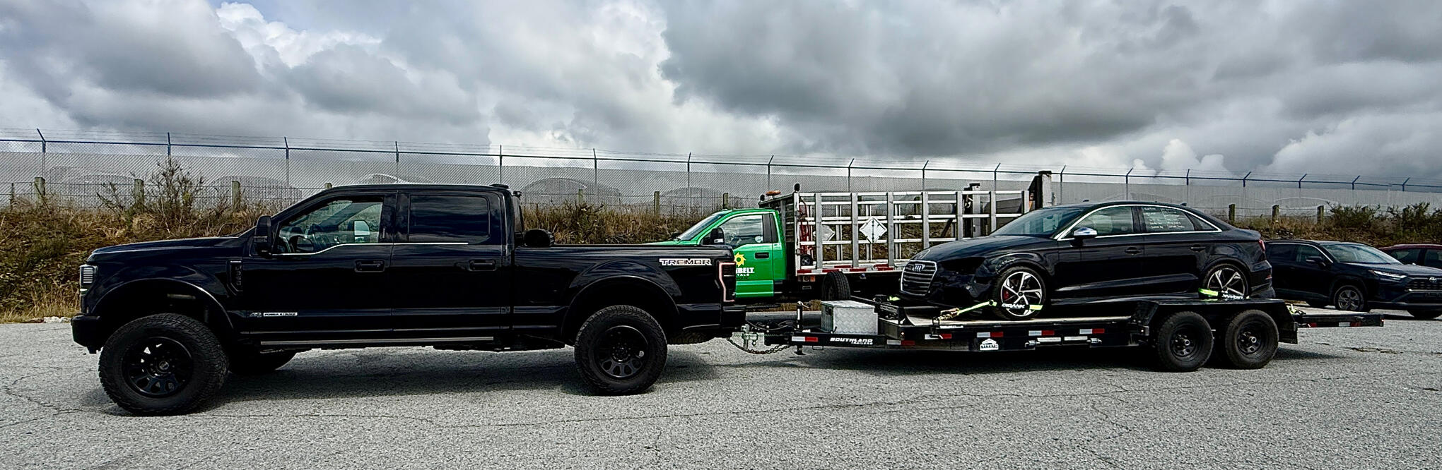 Tow rig hauling the salvage Audi S3 on a trailer at the auction lot